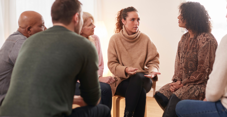 Image of a group of people seated in a circle having a discussion.