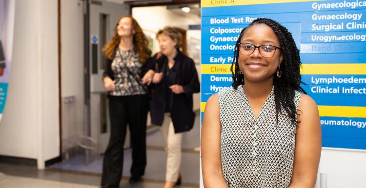 A woman standing infront of a sign in a hospital 