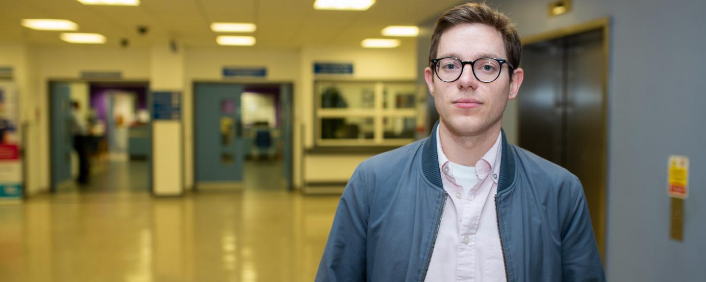 Young man standing face on to camera in a hospital hallway