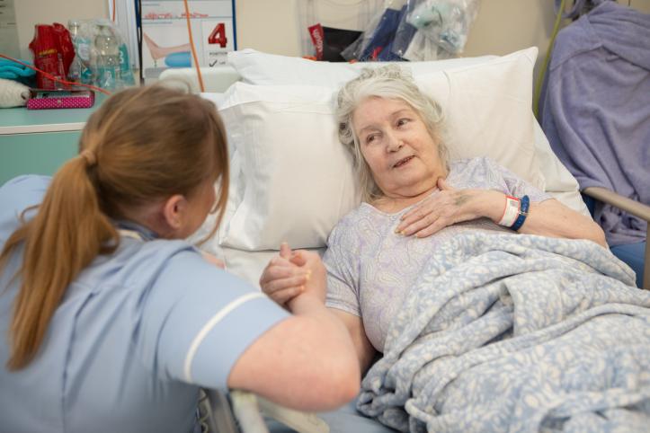 Woman in hospital bed talking to nurse