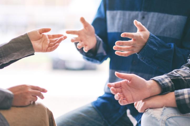 Close-up of several people’s hands gesturing toward each other during a conversation, suggesting discussion or collaboration.