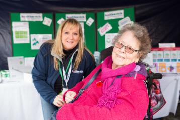 Healthwatch staff member at event talking to someone in a wheelchair