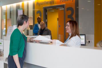 Woman speaking to someone at the hospital reception