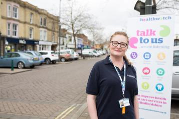 Healthwatch Staff member infront of some branded promotional material at a Healthwatch event