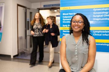 A woman standing infront of a sign in a hospital 