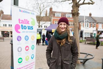 Healthwatch Staff member infront of some branded promotional material at a Healthwatch event