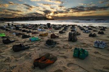 94 pairs of empty shoes on a beach