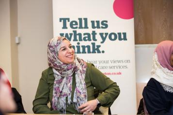 Woman in headscarf infront of a Healthwatch banner that says 'Tell us what you think'