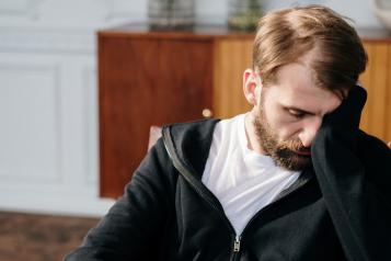 Man sitting in chair with head in hands