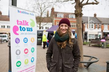 Student volunteer standing infront of a Healthwatch banner