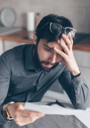 Man with glasses on head reading letter and looking confused