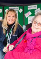 Healthwatch staff member at event talking to someone in a wheelchair