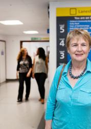 Woman standing infront of a hospital sign that shows all the different departments