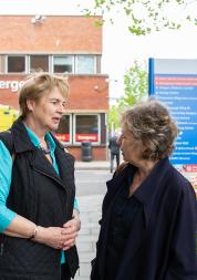 Two older women talking outside a hospital