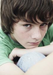 Young boy sitting down hugging his knees